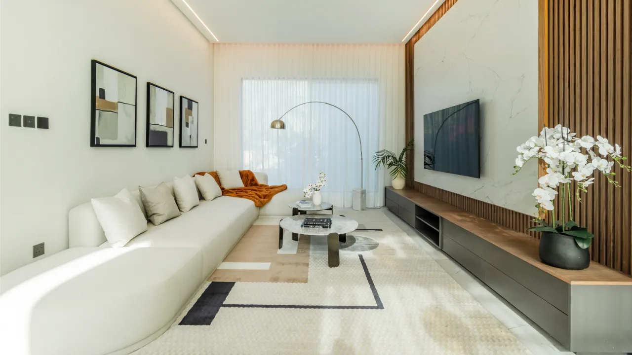 Modern living room with stylish TV wall design and a long sofa after a complete house refurbishment by Arta Group in Dubai